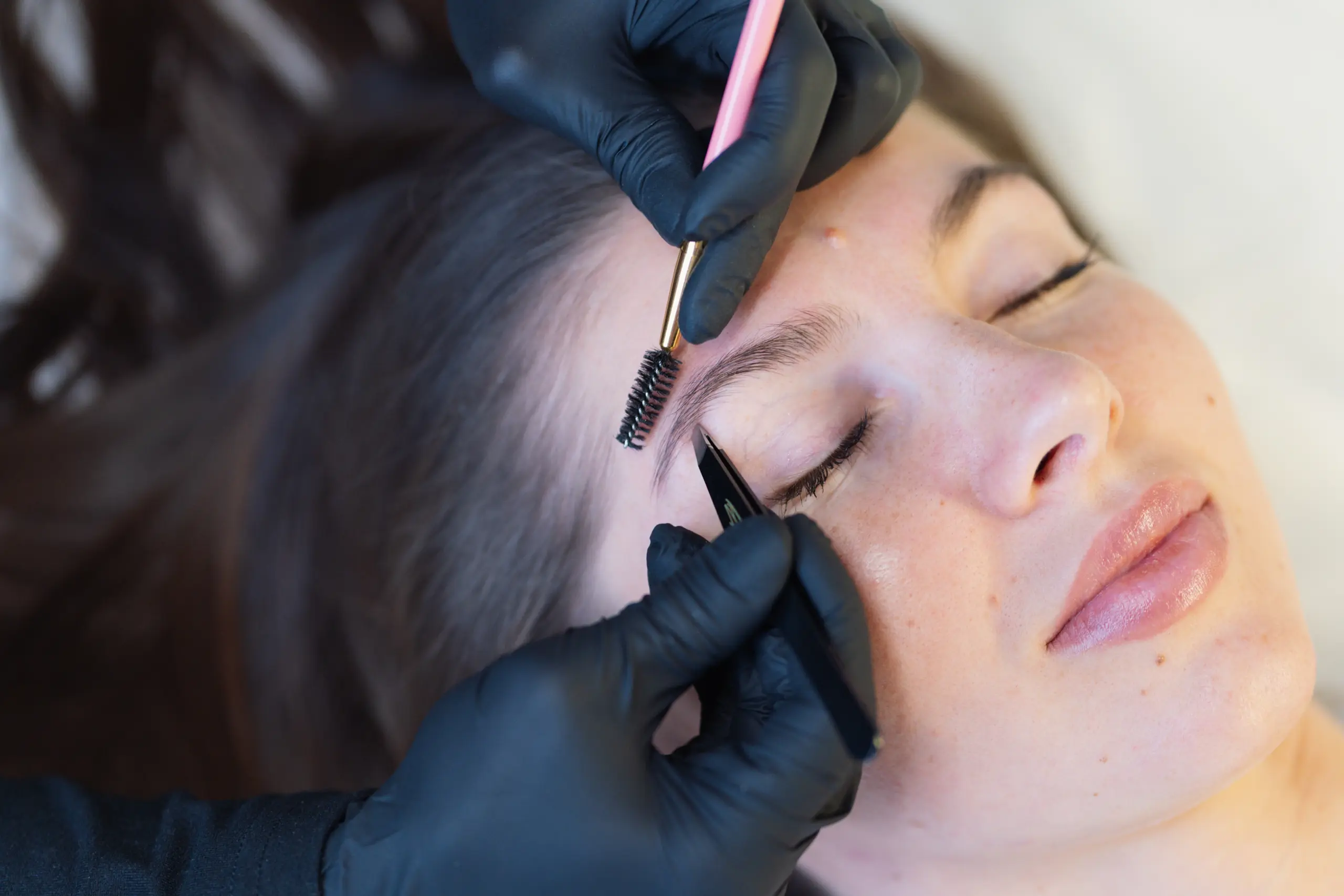 A professional carefully shaping a client’s eyebrow